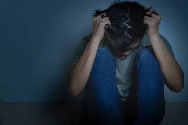 Homem triste abraçar o joelho e chorar sentado sozinho em um quarto escuro. Depre — Fotografia de Stock