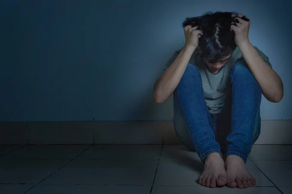 Homem triste abraçar o joelho e chorar sentado sozinho em um quarto escuro. Depre — Fotografia de Stock