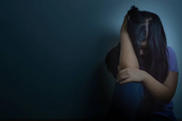 Smutna kobieta przytula kolano i płacze samotnie w ciemnym pokoju. Grupa robocza — Zdjęcie stockowe