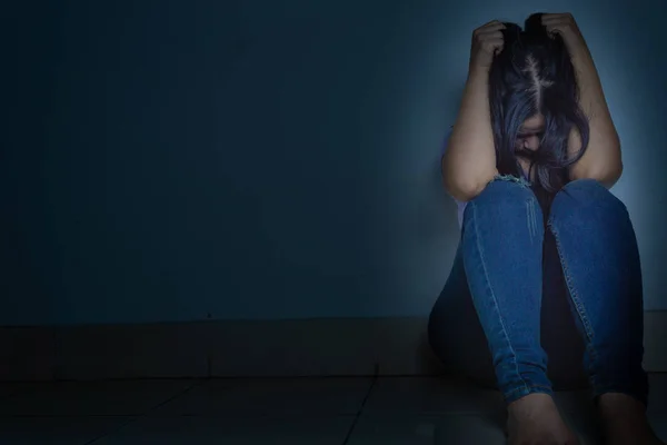 Traurige Frau umarmt ihr Knie und weint allein in einem dunklen Raum sitzend. dep — Stockfoto