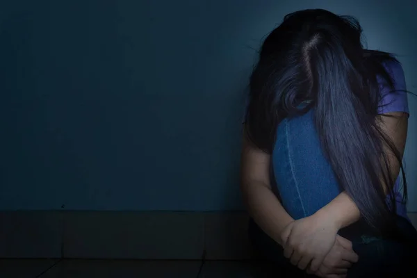 Mujer triste abrazar su rodilla y llorar sentado solo en una habitación oscura. Dep. —  Fotos de Stock