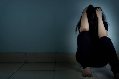 Üzgün kadın, karanlık bir odada tek başına otururken dizine sarılıp ağlar. Dep.