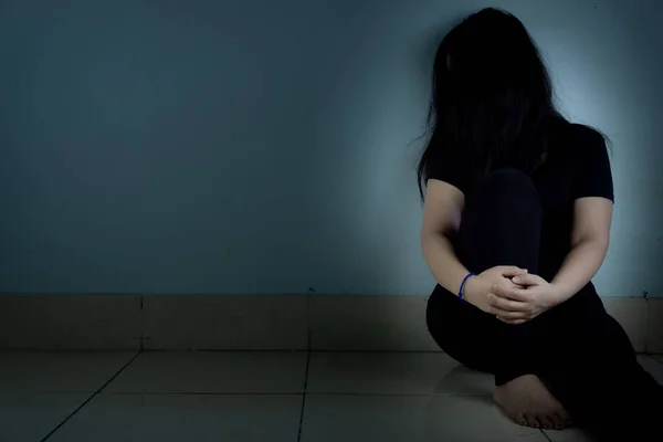 Szomorú nő öleli térdét és sír ül egyedül egy sötét szobában. Dep. — Stock Fotó