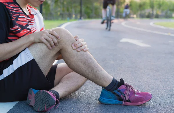 Lesões no joelho. Jovem homem esporte segurando joelho com as mãos em pa — Fotografia de Stock