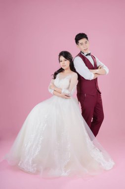 Pembe arka planda mutlu gelin ve damat. Düğün çifti, yeni aile, gelinlik. Gelin düğünü. Aşk konsepti