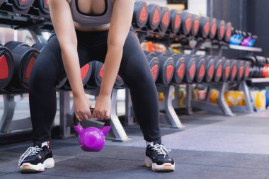 Genç sporcu kadın spor salonunda kettlebell ile Sumo çömelmesi yapıyor. Spo