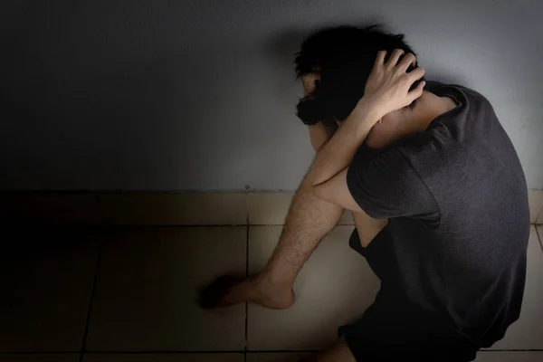 Sad man hug his knee and cry sitting alone in a dark room. Depre — Stock Photo, Image