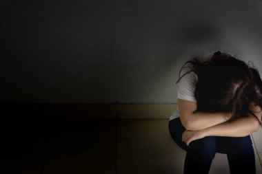 Üzgün kadın, karanlık bir odada tek başına otururken dizine sarılıp ağlar. Dep.