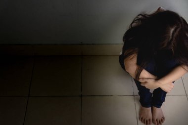 Üzgün kadın, karanlık bir odada tek başına otururken dizine sarılıp ağlar. Dep.