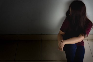 Üzgün kadın, karanlık bir odada tek başına otururken dizine sarılıp ağlar. Dep.