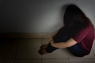 Üzgün kadın, karanlık bir odada tek başına otururken dizine sarılıp ağlar. Dep.