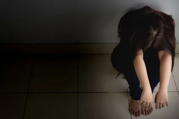 Femme triste étreindre son genou et pleurer assis seul dans une pièce sombre. Dép. — Photo