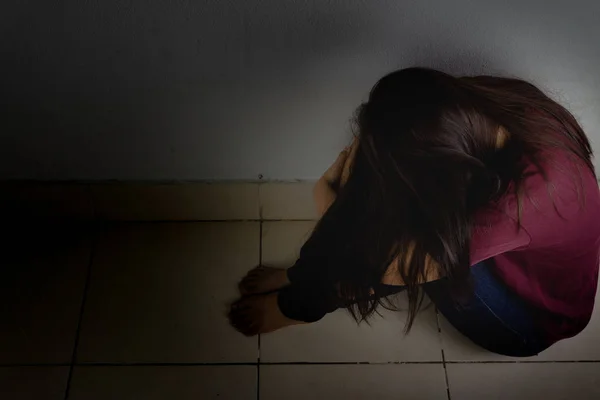 Donna triste abbracciare il ginocchio e piangere seduto da solo in una stanza buia. Dep — Foto Stock