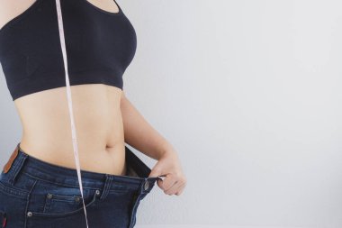 Close up shot of woman with slim body measuring her waistline an