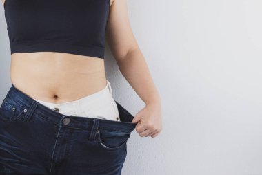 Close up shot of woman with slim body showing her diet results. 