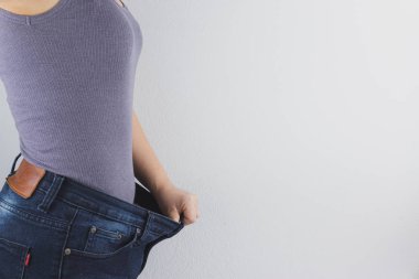 Close up shot of woman with slim body showing her diet results. 