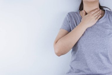 Boğazı ağrıyan kadın eli boynuna dokunuyor..