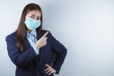 Koronavirüse karşı koruyucu maske takan iş kadını 2,5 yaşında ve soğuk. Ve parmağı beyaz arkaplanı gösteriyor..