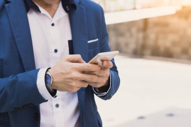 Yakın plan iş adamı modern şehirdeki akıllı telefonu tutuyor ve işaret ediyor. İş ve finans kavramı.