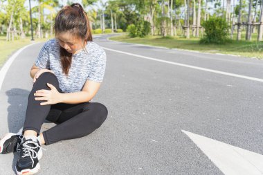 Asyalı bir kadın parkta koşarken dizinden yaralanmış, spor konseptinden yaralanmış..
