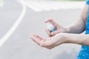 Yakın plan erkek, yolda koronavirüs hastalığını korumak için ellerini yıkamak için alkol spreyi kullanıyor. Coronavirus Hastalığı sırasındaki kavram COVID-19.