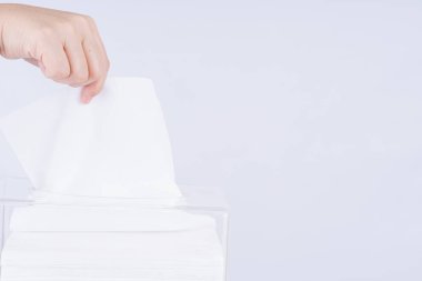 Şeffaf bir kristal doku kutusundan beyaz bir kağıt parçası çıkaran narin kadın elleri..