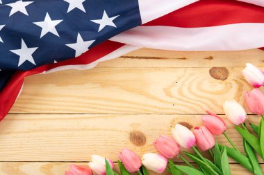 Tahta arka planda lale çiçeği olan Amerikan bayrağı. ABD Anma Günü, Başkanlar Günü, Gaziler Günü, İşçi Bayramı, Bağımsızlık Günü ya da 4 Temmuz kutlamaları için. Üst görünüm, metin için boşluk kopyala.