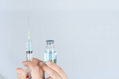 Kadın doktor ya da bilim adamının elinde şırınga ve ilaç aşısı şişesi var. COVID 19 veya koronavirüs konsepti.