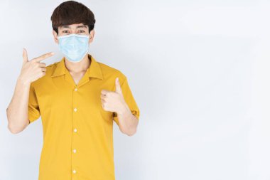 Koronavirüsü korumak için tıbbi koruma maskesi takan Asyalı yakışıklı, mutlu hipster adam, başbakanın tozunu filtrele ve soğuktan dondur ve beyaz arka planda onlarla savaşmak için elini kaldır.