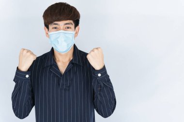 Koronavirüsü korumak için tıbbi koruma maskesi takan Asyalı yakışıklı, mutlu hipster adam, başbakanın tozunu filtrele ve soğuktan dondur ve beyaz arka planda onlarla savaşmak için elini kaldır.