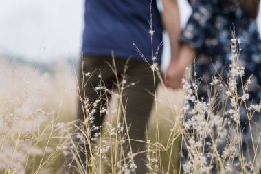 Güneşli bir günde çayırda ayakta dikilen ve birbirlerine tutunan çift. Çiftler yaz tatilinde eğleniyorlar..