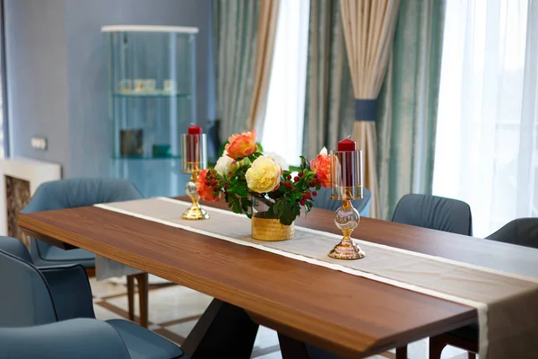 Large dining table with a tablecloth and two candles.