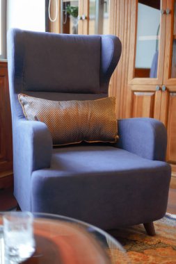 Klasik bir ofiste mavi koltuk. Dekor elemanı. Koltukta altın bir yastık yatıyor..