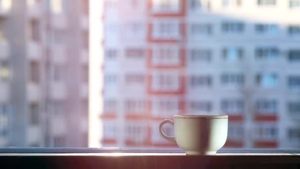 窗台上的一杯热茶 外面结了霜 杯子里发出的蒸汽清晰可见 在城市景观的背景下 背景在Bokeh 杯子是白的 — 图库视频影像