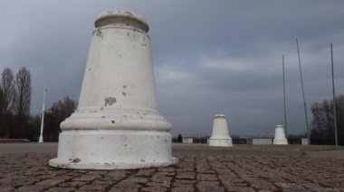 Şehir meydanındaki eski beyaz sütunlar. Bakış açısına göre üç sütun. Kasvetli bulutlar gökyüzünde dolaşıyor, periyodik olarak güneş çerçeveye yükseliyor. Göz kamaştırıcı. Timelapse 4 K. Şehir manzarası ufukta görünüyor..