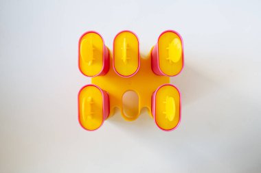 Sarı şapkalı pembe dondurma kutuları. Dondurma için beş form beyaz arka planda duruyor. Sarı başlıklar içinde. Yukarıdan bak. Dondurma yapıyorum..