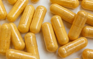 Beyaz arka planda Oval sarı haplar. Yakınlarda bir sürü hap var. Hastalıklara karşı savaş. İnsan sağlığı. İlaç sanayisi. İlaçlar, vitaminler, tabletler..