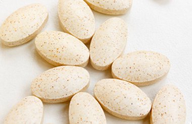Beyaz arka planda yuvarlak sarı benekli haplar. Yakınlarda bir sürü hap var. Hastalıklara karşı savaş. İnsan sağlığı. İlaç sanayisi. İlaçlar, vitaminler, tabletler..