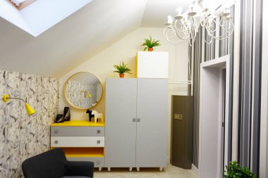 Sarı tonlarda bir yatak odasının iç tasarımı. İçinde at ve vazo figürleri olan sarı komodin. Dolabın ortasında, kapalı alandaki bitkilerin raflarında. Tavanda, girişte, odanın köşesinde büyük bir kasa var..