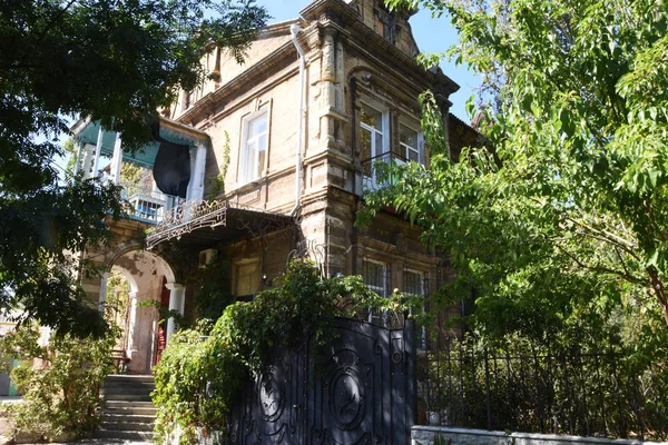 Old mansion, entrance through an iron gate. Around grow tall, ol