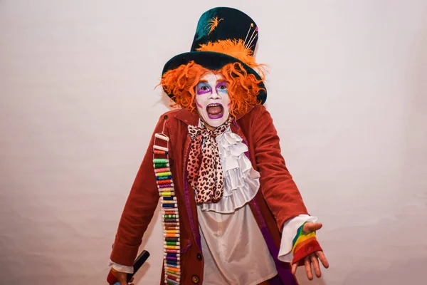 A young man in a hatter costume is dancing in the room, entertaining guests. Fun and enthusiasm expressed by a young actor.
