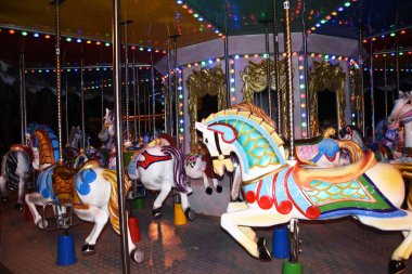 Bir eğlence parkında, bir sokak gecesinde, renkli ışıkların ışığında, atlı karınca dönüyor. Atlı karınca gibi bir at çocukları neşelendirir..