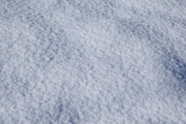 Yeni yağmış saf kardan oluşan kar beyazı bir arka plan. Güneş karlı bir yüzeyde parlıyor ve kar kristallerinde parıldıyor..