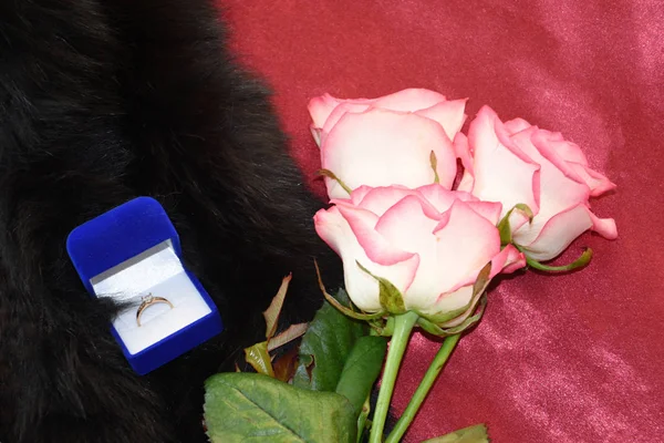 Three pink roses, an engagement ring and a fur coat made of natural fur are three desirable things for a woman on a holiday. Gifts to beloved women.