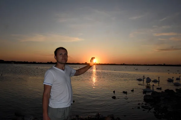 Молодой Человек Стоит Огромного Озера Белыми Лебедями Пытается Поймать Солнце — стоковое фото