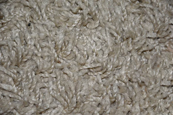 Part of a long-pile carpet of light brown color.