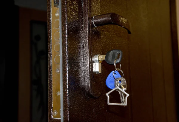 The front door is ajar, there are keys in the lock, the concept of receiving or buying an apartment. The concept of inattention and forgetfulness of old people leaving keys in the lock.