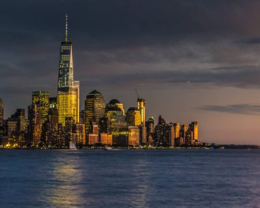 New York, New York / ABD - 14 Ekim 2015: Aşağı Manhattan siluetinin günbatımı görüntüsü. Dünya Ticaret Merkezi ve Hudson Nehri 'ndeki yansımaları gösteriyor..