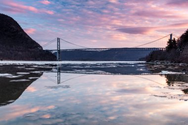 Fort Montgomery, New York / ABD - 26 Ocak 2020: Sunset 'teki Bear Mountain Köprüsü manzarası. Bulutlar ve köprü Hudson Nehri 'ne yansıyor.