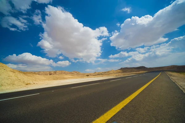 Aszfaltúton, a júdeai sivatagban, a háttér a kék ég, a felhők — Stock Fotó